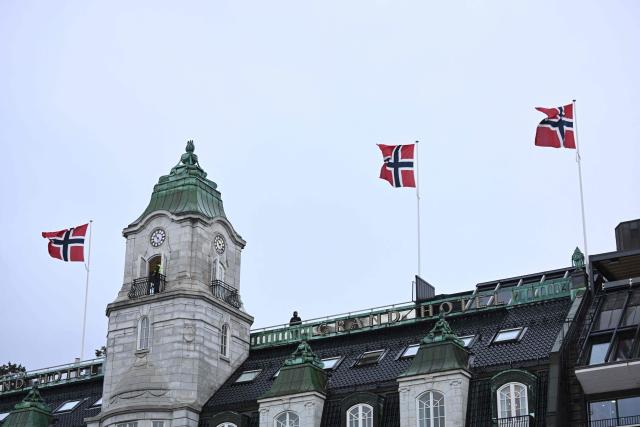A policeman watches out from a tower close to Norway's parliament, with national flags on the roof of the building in Oslo, Norway, where Ukraine's President is expected to attend a parliament session on October 21, 2026, one day after a meeting in the Norwegian capital on the situation in Ukraine. Ukrainian President Volodymyr Zelensky arrived in Oslo on October 20, 2026 for talks with top US envoys. (Photo by Jonathan Nackstrand / AFP)