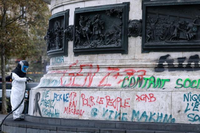 A city hall employee removes graffitis from the Place de la Republique statue four days after riots and looting occurred on the sidelines of nationwide protests against the "high cost of living". (Photo by Kenzo TRIBOUILLARD / AFP)