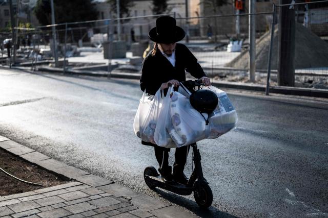 An ultra-Orthodox Jewish man balances bags of groceries on an electric scooter as he rides along a street in Jerusalem on October 21, 2026, ahead of Israel's legislative election. Israel heads to the polls on October 27 in its first election since the October 7, 2023 Hamas-led attack, in what is seen as a referendum on the prime minister. (Photo by Jewel SAMAD / AFP)