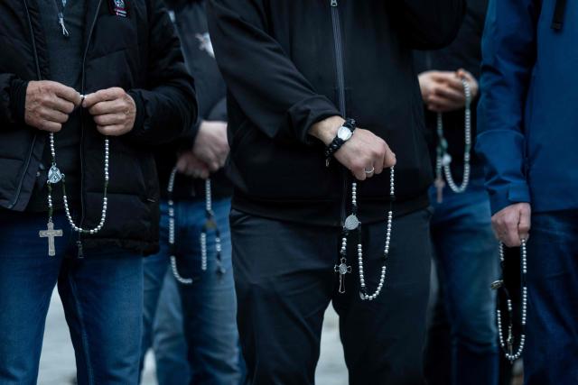 Pro-life activists hold rosaries at a rally and rosary prayer organised by conservative groups opposed to loosening abortion laws in Poland, in front of the Polish Parliament in central Warsaw, as the banner in the background reads “Genocide”, on October 21, 2026. Poland's parliament voted on Tuesday to liberalise abortion laws in the traditionally Catholic country, which has some of the EU's most restrictive rules on ending pregnancies. (Photo by Wojtek RADWANSKI / AFP)