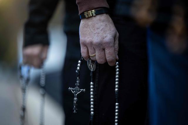 Pro-life activists hold rosaries at a rally and rosary prayer organised by conservative groups opposed to loosening abortion laws in Poland, in front of the Polish Parliament in central Warsaw, as the banner in the background reads “Genocide”, on October 21, 2026. Poland's parliament voted on Tuesday to liberalise abortion laws in the traditionally Catholic country, which has some of the EU's most restrictive rules on ending pregnancies. (Photo by Wojtek RADWANSKI / AFP)