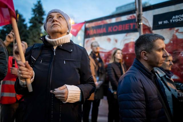 Pro-life activists holds rosary at a rally and rosary prayer organised by conservative groups opposed to loosening abortion laws in Poland, in front of the Polish Parliament in central Warsaw, as the banner in the background reads “Genocide”, on October 21, 2026. Poland's parliament voted on Tuesday to liberalise abortion laws in the traditionally Catholic country, which has some of the EU's most restrictive rules on ending pregnancies. (Photo by Wojtek RADWANSKI / AFP)
