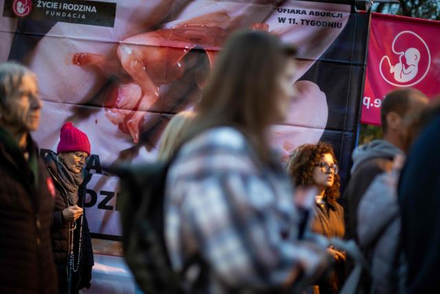 Pro-life activists holds rosary at a rally and rosary prayer organised by conservative groups opposed to loosening abortion laws in Poland, in front of the Polish Parliament in central Warsaw, as the banner in the background reads “Genocide”, on October 21, 2026. Poland's parliament voted on Tuesday to liberalise abortion laws in the traditionally Catholic country, which has some of the EU's most restrictive rules on ending pregnancies. (Photo by Wojtek RADWANSKI / AFP)