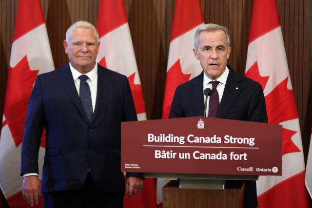 Canada's Prime Minister Mark Carney (R) speaks as Ontario Premier Doug Ford looks on during a press conference on Parliament Hill in Ottawa, Ontario, Canada on October 21, 2026. (Photo by Dave Chan / AFP)