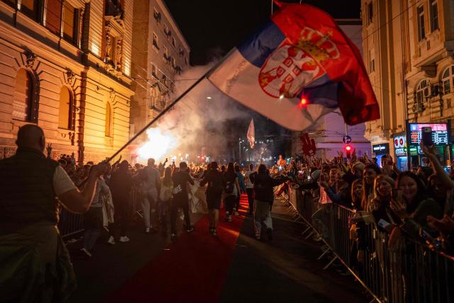 Students wave a giant Serbian flag as they are greeted by residents upon their arrival in central Belgrade on October 21, 2026, after walking for several days to attend the student movement's final major rally, due to be held in the capital the following day, ahead of Serbia's October 25 snap elections. The student-led movement emerged from nationwide protests following the November 2024 collapse of a railway station canopy in Novi Sad that killed 16 people, with demands expanding to include early elections in May 2025. The student movement formally entered the electoral race in September, challenging the Serbian Progressive Party (SNS). (Photo by Andrej ISAKOVIC / AFP)