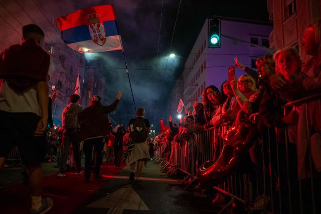 Students wave a giant Serbian flag as they are greeted by residents upon their arrival in central Belgrade on October 21, 2026, after walking for several days to attend the student movement's final major rally, due to be held in the capital the following day, ahead of Serbia's October 25 snap elections. The student-led movement emerged from nationwide protests following the November 2024 collapse of a railway station canopy in Novi Sad that killed 16 people, with demands expanding to include early elections in May 2025. The student movement formally entered the electoral race in September, challenging the Serbian Progressive Party (SNS). (Photo by Andrej ISAKOVIC / AFP)