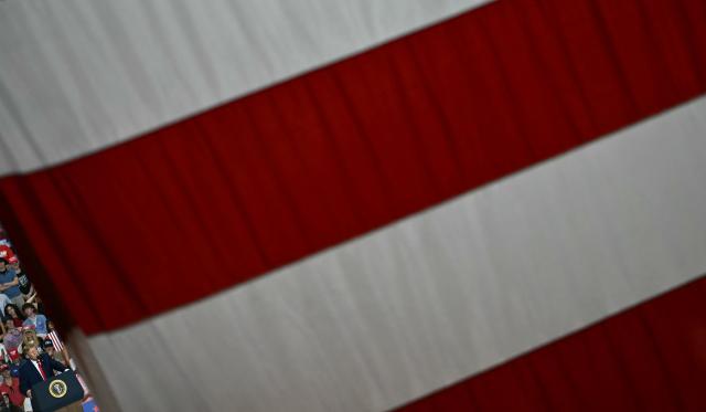 Stripes from a US flag are seen as US President Donald Trump speaks during a campaign rally at T. Ed Garrison Arena in Pendleton, South Carolina on October 21, 2026. (Photo by Kent NISHIMURA / AFP)