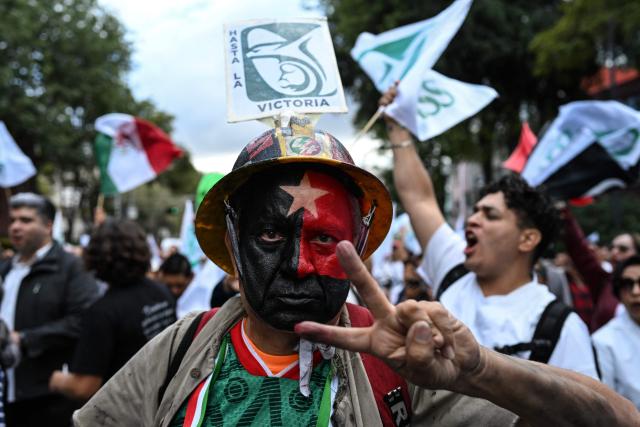 A union member makes a V-for-victory sign during a protest march by workers from the Mexican Social Security Institute (IMSS) demanding better wages and the provision of medications for patients at hospitals across Mexico City on October 21, 2026. (Photo by Yuri CORTEZ / AFP)