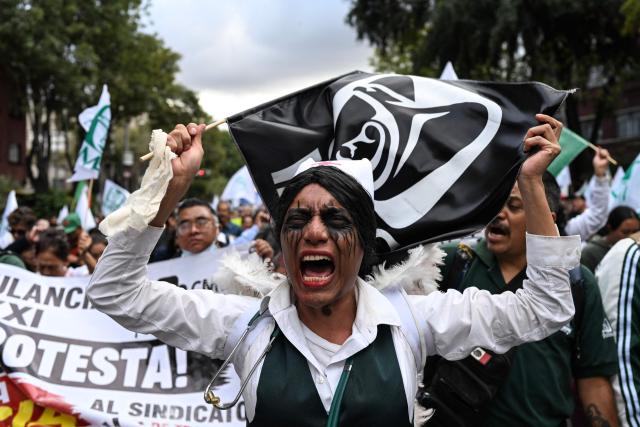 A nurse working for the Mexican Social Security Institute (IMSS), with her face painted, shouts slogans during a protest march demanding better wages and medications for patients at various hospitals in Mexico City on October 21, 2026. (Photo by Yuri CORTEZ / AFP)