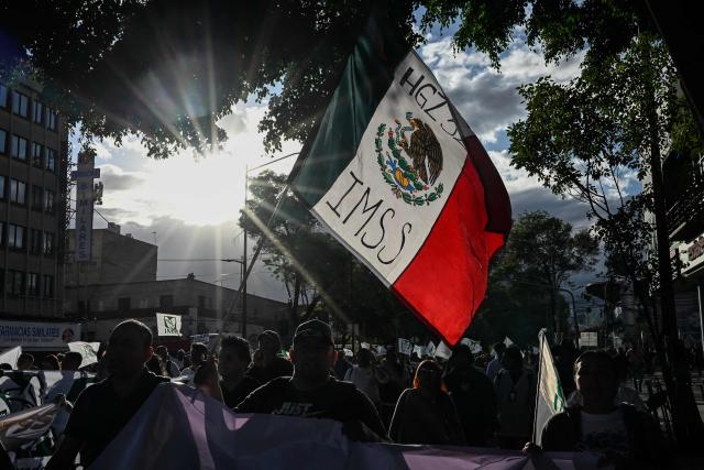 Health workers from the Mexican Social Security Institute (IMSS) shout slogans during a protest march demanding better wages and medications for patients at various hospitals in Mexico City on October 21, 2026. (Photo by Yuri CORTEZ / AFP)