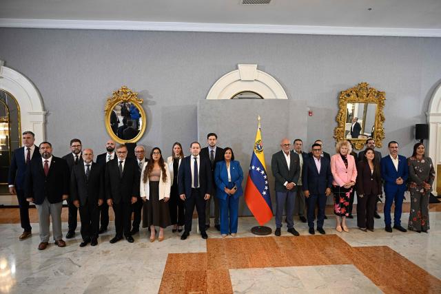 Opposition delegation head Dinorah Figuera (C-R) and Venezuelan National Assembly President Jorge  Rodriguez (C-L) their respective delegation members, pose for an official photo at the closing of the third round of political dialogue talks at the Melia hotel in Caracas on  on October 21, 2026. Venezuela's interim government and the opposition on Wednesday reaffirmed their commitment to holding presidential elections in the country under Washington-backed talks, the opposition said after a third round of negotiations. (Photo by Federico PARRA / AFP)