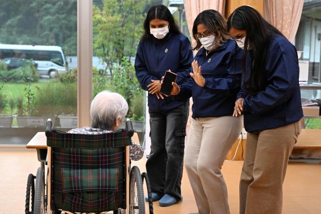 Belen mayor Lina Arista Lopez (2nd R), Wendy Sangama (2nd L) and Ketsi Yahuarcani (R), guests from Peru's Belen district, interact with a resident during a visit to a care-giving facility in Nanmoku village, Japan's Gunma prefecture on September 26, 2026. In a misty mountain village in Japan, residents recently welcomed unlikely guests from a Peruvian district along the Amazon River, seeing a chance to revive an ageing community facing extinction. Nanmoku village officials hope a sister-city agreement, which promotes cultural and people-to-people ties, will ultimately attract young people from Belen to live in Nanmoku, although how they might obtain residency remains unclear. (Photo by Rie KIKUCHI / AFP) / To go with AFP story Japan-Peru-social-population-demographics, FOCUS by Natsuko Fukue and Junior Raborg