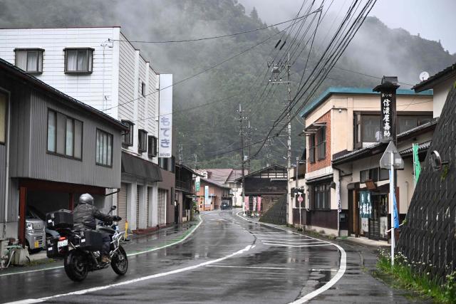 A motorcylist rides through a street in Nanmoku village, Gunma prefecture on September 26, 2026. In a misty mountain village in Japan, residents recently welcomed unlikely guests from a Peruvian district along the Amazon River, seeing a chance to revive an ageing community facing extinction. Nanmoku village officials hope a sister-city agreement, which promotes cultural and people-to-people ties, will ultimately attract young people from Belen to live in Nanmoku, although how they might obtain residency remains unclear. (Photo by Rie KIKUCHI / AFP) / To go with AFP story Japan-Peru-social-population-demographics, FOCUS by Natsuko Fukue and Junior Raborg
