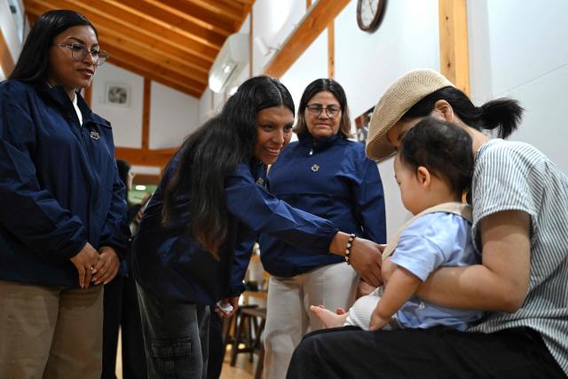 (From L-R) Ketsi Yahuarcani, Wendy Sangama, and Belen mayor Lina Arista Lopez, guests from Peru's Belen district, interact with a baby in Nanmoku village, Japan's Gunma prefecture on September 26, 2026. In a misty mountain village in Japan, residents recently welcomed unlikely guests from a Peruvian district along the Amazon River, seeing a chance to revive an ageing community facing extinction. Nanmoku village officials hope a sister-city agreement, which promotes cultural and people-to-people ties, will ultimately attract young people from Belen to live in Nanmoku, although how they might obtain residency remains unclear. (Photo by Rie KIKUCHI / AFP) / To go with AFP story Japan-Peru-social-population-demographics, FOCUS by Natsuko Fukue and Junior Raborg