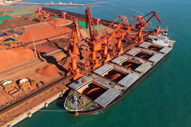 A cargo ship unloads imported iron ore at a port in Qingdao, in China’s eastern Shandong province on October 22, 2026. (Photo by CN-STR / AFP) / China OUT