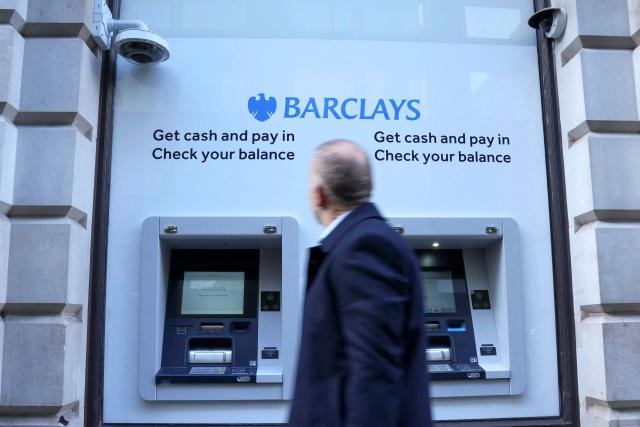 (FILES) This photo taken on January 30, 2026 shows a pedestrian walking past Barclays branded ATMs (automated teller machines) in London. British bank Barclays on October 22, 2026 announced plans to cut around 5,000 jobs, or roughly five percent of its global workforce, as it leans on artificial intelligence to become more efficient. (Photo by CARLOS JASSO / AFP)