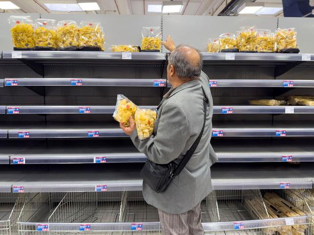 A man grabs packets of pasta from above empty shelves in a supermarket suffering a disruption in supplies following road blockades by Italy's hauliers in Quarto, near Naples, on October 21, 2026. The protest by truck drivers, who are demonstrating against rising fuel costs, began on 16 October in the southern regions of Italy and is bringing the country to a standstill, disrupting fuel supplies to petrol stations and food supplies to supermarkets. (Photo by ELIANO IMPERATO / AFP)