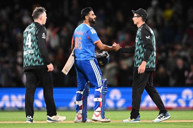India's Naman Dhir (C) shakes hands with New Zealand's Mitchell Santner (R) after winning the first T20 international cricket match between New Zealand and India at Hagley Oval in Christchurch on October 22, 2026. (Photo by Sanka VIDANAGAMA / AFP)