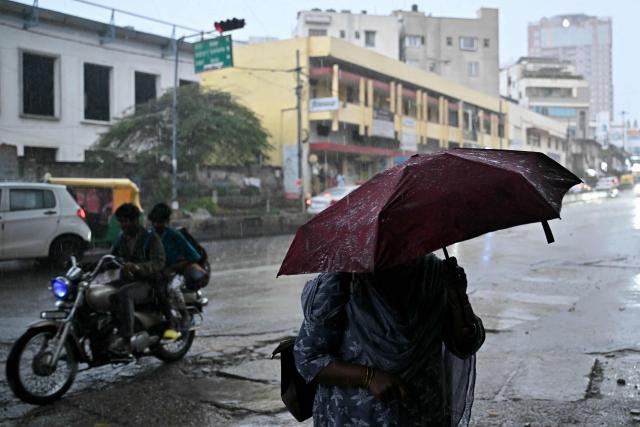 A pedestrian carrying an umbrella walks during rainfall in Bengaluru on October 22, 2026. (Photo by Idrees MOHAMMED / AFP)