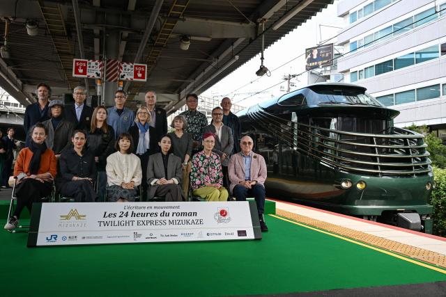 (From L, front) French novelist Muriel Barbery, French writer Claire Berest, Japanese writer Machi Tawara, Japanese writer Mariko Asabuki, Japanese author Anna Ogino, French writer Paul Fournel and (From L, middle) Japanese writer Hitonari Tsuji, Japanese novelist Hitomi Kanehara, "L'Ecriture en mouvement" Association Founder Anne Forrest-Wilson, Japanese author Kaori Ekuni, French poet Frederic Forte and (From L, rear) French writer Christophe Ono-dit-Biot, Japanese poet Hisaki Matsuura, Argentine writer Eduardo Berti, French writer Herve Le Tellier, Japanese author Toh EnJoe, French author Richard Collasse pose for a group photo at Shin-Osaka station in Osaka prefecture on October 22, 2026. Sixteen writers -- half French-speaking and half Japanese -- boarded a luxury train in Kyoto on October 22, 2026, faced with the unusual task of collectively writing a novel in under 24 hours. (Photo by Rie KIKUCHI / AFP) / To go with 'JAPAN-FRANCE-LITERATURE-TRANSPORT-TOURISM' Reportage by Julien GIRAULT