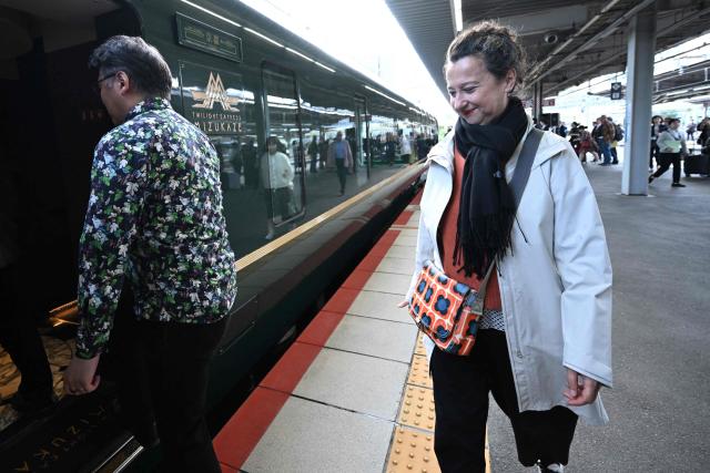 French novelist Muriel Barbery boards the Twilight Express Mizukaze after posing for a group photo at Shin-Osaka Station in Osaka Prefecture on October 22, 2026. Sixteen writers -- half French-speaking and half Japanese -- boarded a luxury train in Kyoto on October 22, 2026, faced with the unusual task of collectively writing a novel in under 24 hours. (Photo by Rie KIKUCHI / AFP) / To go with 'JAPAN-FRANCE-LITERATURE-TRANSPORT-TOURISM' Reportage by Julien GIRAULT
