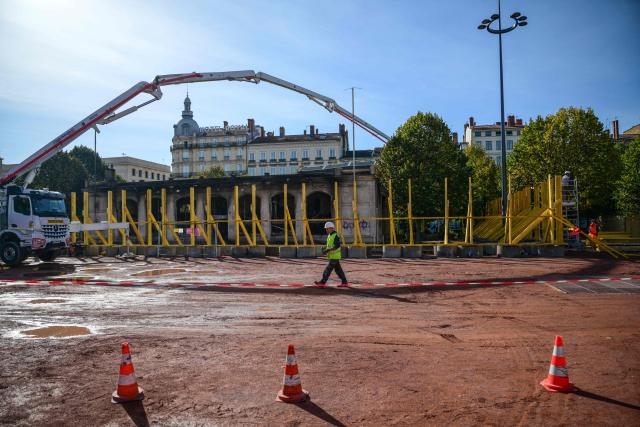 Workers secure the perimeter in Lyon, central-eastern France, on October 22, 2026, ahead of the start of repair work on the tourist information centre on Place Bellecour, which had been set alight by protesters on October 17. (Photo by OLIVIER CHASSIGNOLE / AFP)