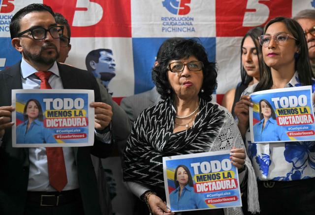Members of Citizen Revolution (CR) party hold signs during a press conference following the arrest of its former presidential candidate Luisa Gonzalez, at the party headquarters in Quito, Ecuador on October 22, 2026. Gonzalez, who had been under investigation by authorities since January over alleged irregular funding from Venezuela for her 2023 campaign, was arrested on October 22, 2026, in Manabi, although the police confirmed her detention without specifying the reasons. (Photo by Rodrigo BUENDIA / AFP)