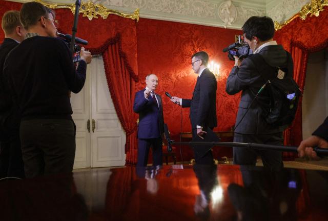 In this pool photograph distributed by the Russian state agency Sputnik, Russia's President Vladimir Putin answers a question of Russian journalist Pavel Zarubin after giving a speech during a festive gathering marking the 150th anniversary of the Russian Union of Theatre Workers at the Bolshoi Theatre in Moscow on October 22, 2026. (Photo by Gavriil Grigorov / POOL / AFP)