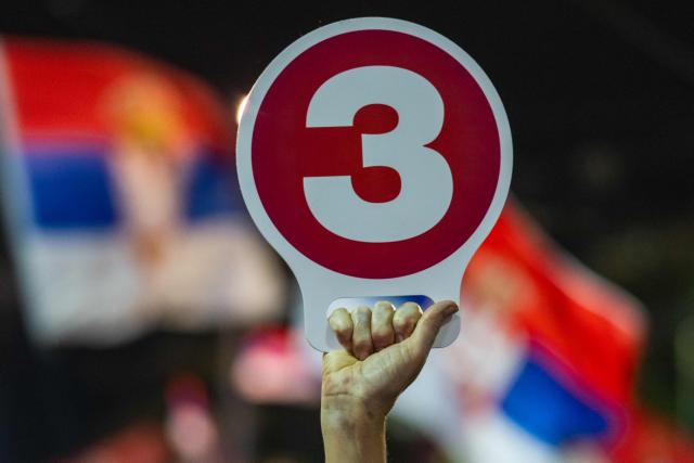 A Serbia's student-led movement supporter holds a placard with the number three, the student-backed election list's ballot number, attends the final campaign rally of the student-backed election list in central Belgrade on October 22, 2026, ahead of the country's snap parliamentary elections on October 25. The vote follows nearly two years of student-led protests sparked by the November 2024 collapse of a railway station canopy in Novi Sad that killed 16 people, with demands for early elections becoming a central goal of the movement. The student-backed list is challenging the ruling Serbian Progressive Party (SNS), led in the campaign by former president Aleksandar Vucic, who resigned in September to run for prime minister. (Photo by Andrej ISAKOVIC / AFP)