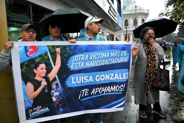 Supporters of former Ecuadorian presidential candidate Luisa Gonzalez hold a banner reading "Another victim of this narco-dictatorship. Luisa Gonzalez, we support you" outside the Flagrancy Unit in Quito on October 22, 2026, following her arrest. Ecuador's opposition on October 22, 2026, accused US-backed President Daniel Noboa of running a "dictatorship" following the arrest of former presidential candidate Luisa Gonzalez, the latest left-wing figure to face legal proceedings. (Photo by Rodrigo BUENDIA / AFP)