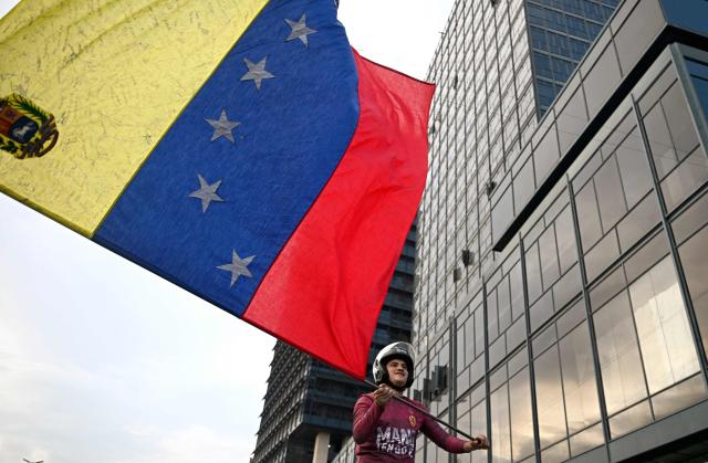 A supporter of Venezuelan opposition leader and Nobel Peace Prize winner Maria Corina Machado waves a Venezuelan flag during a rally to demand elections in Caracas on October 22, 2026. (Photo by Federico PARRA / AFP)