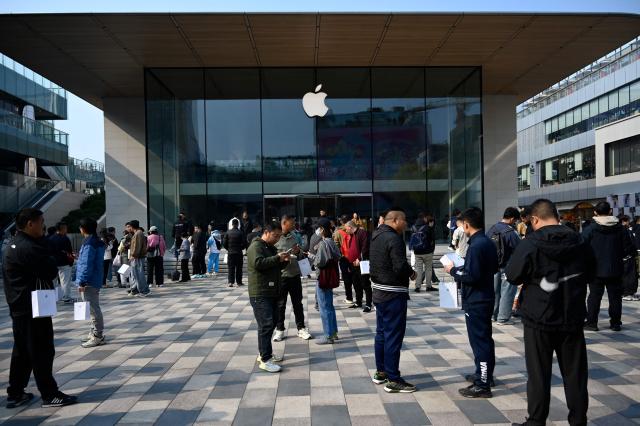 People stand outside an Apple store as the iPhone Duo goes on sale in China, in Beijing on October 23, 2026. (Photo by WANG Zhao / AFP)