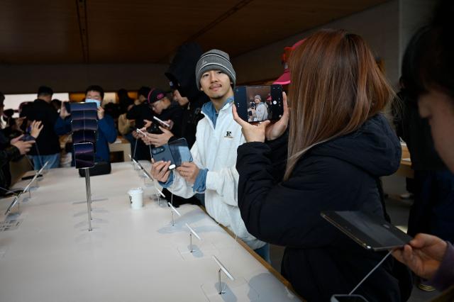 People look at the iPhone Duo at an Apple store in Beijing on October 23, 2026. (Photo by WANG Zhao / AFP)