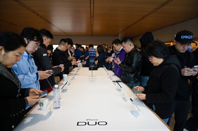 People look at the iPhone Duo at an Apple store in Beijing on October 23, 2026. (Photo by WANG Zhao / AFP)