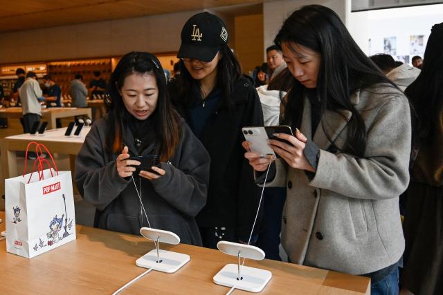 People look at the iPhone Duo at an Apple store in Beijing on October 23, 2026. (Photo by WANG Zhao / AFP)