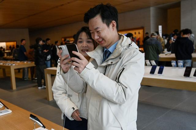 People look at the iPhone Duo at an Apple store in Beijing on October 23, 2026. (Photo by WANG Zhao / AFP)