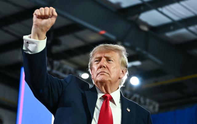 US President Donald Trump gestures during a midterm election campaign rally at Sioux Gateway Airport in Sioux City, Iowa on October 22, 2026. President Trump is travelling the country to try to give a boost to Republicans in tight midterm races. (Photo by Kent NISHIMURA / AFP)