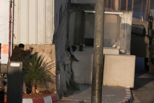 EDITORS NOTE: Graphic content / One of two armed Palestinian men (L) points his handgun while exchanging fire with Israeli forces at the northern checkpoint of Hebron, in the Israeli-occupied West Bank, on October 23, 2026. Israeli troops on October 23 shot dead two suspected Palestinian assailants in the West Bank after a shooting that left at least five people wounded, officials said. (Photo by HAZEM BADER / AFP)