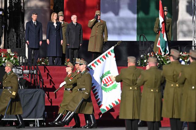 Hungarian President Andras Baka (3rd L), the Speaker of the Hungarian Parliament Agnes Forsthoffer (2nd L) and Hungarian Prime Minister Peter Magyar (L) stand in front of the parliament building in Budapest, Hungary, on October 23, 2026, during a ceremony to mark the 70th anniversary of the Hungarian Revolution of 1956, also known as the Hungarian Uprising against the Soviet communist regime. (Photo by Attila KISBENEDEK / AFP)