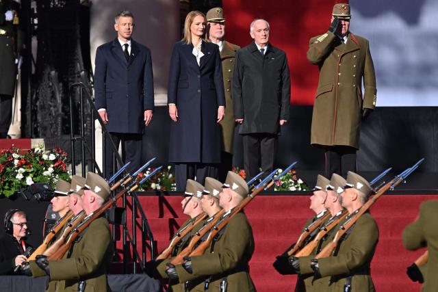 Hungarian President Andras Baka (3rd L), the Speaker of the Hungarian Parliament Agnes Forsthoffer (2nd L) and Hungarian Prime Minister Peter Magyar (L) stand in front of the parliament building in Budapest, Hungary, on October 23, 2026, during a ceremony to mark the 70th anniversary of the Hungarian Revolution of 1956, also known as the Hungarian Uprising against the Soviet communist regime. (Photo by Attila KISBENEDEK / AFP)