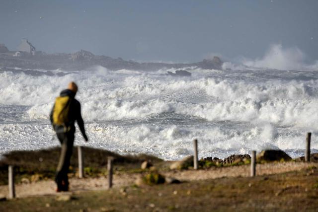 A man walks near the waves at Pointe de la Torche in Plomeur, western France, as storm Austen hits the coasts of France. (Photo by Fred TANNEAU / AFP)