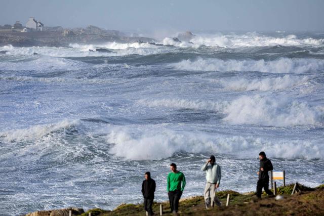 People walk near the waves at Pointe de la Torche in Plomeur, western France, as storm Austen hits the coasts of France. (Photo by Fred TANNEAU / AFP)