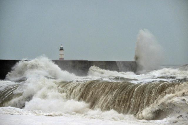Waves crash over onto the beach near Newhaven Lighthouse and the breakwater in Newhaven, southern England on October 23, 2026, as Storm Austen brought strong winds and heavy rain across much of southern England. Storm Auste (Photo by GLYN KIRK / AFP)