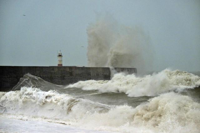 Waves crash over onto the beach near Newhaven Lighthouse and the breakwater in Newhaven, southern England on October 23, 2026, as Storm Austen brought strong winds and heavy rain across much of southern England. Storm Auste (Photo by GLYN KIRK / AFP)