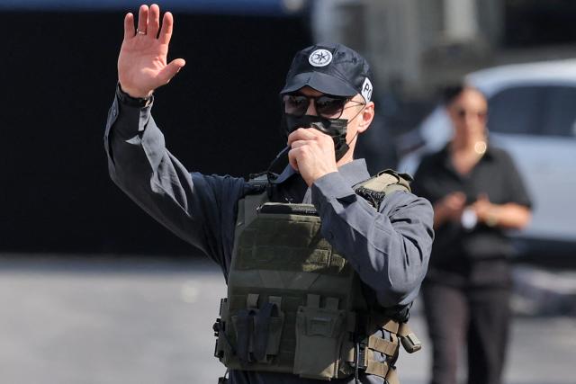 An Israeli policeman gestures at the scene of an earlier fire exchange between armed Palestinians and Israeli forces following an incident at the norther checkpoint of Hebron in the Israeli-occupied West Bank on October 23, 2026. Israeli troops on October 23 shot dead two suspected Palestinian assailants in the West Bank after a shooting that left at least five people wounded, officials said. (Photo by Ahmad GHARABLI / AFP)