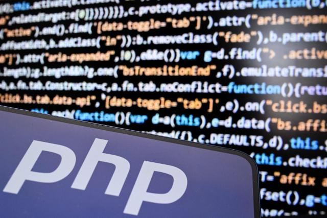 An illustration picture taken on October 23, 2026 shows the PHP (Hypertext Preprocessor) logo on a smartphone screen and a computer code on a laptop screen in Frankfurt am Main, western Germany. Government agencies and companies around the world shut down websites on October 21, 2026 after two critical flaws came to light involving PHP, a programming language that is the basis for a large share of the internet. (Photo by Kirill KUDRYAVTSEV / AFP)