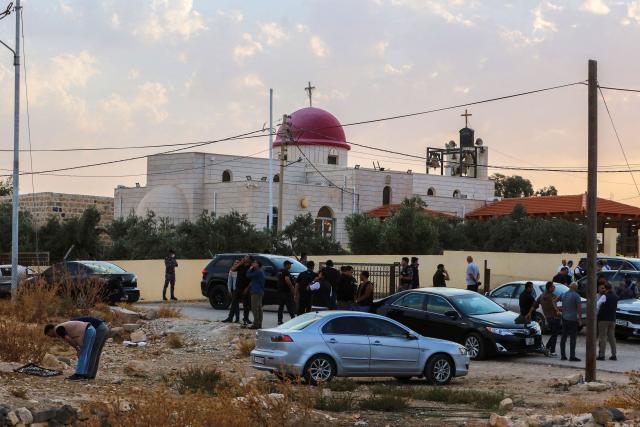 People and security forces gather outside a Greek Orthodox Church in the village of Hammoud village in Jordan's Karak governorate following a shooting on October 23, 2026. Gunmen killed at least seven people and wounded 10 more in an attack on a church in southern Jordan on October 23, authorities said. Two assailants stormed the compound of a Greek Orthodox church in the village of Hammoud in Karak governorate before opening fire, the public security directorate said in a statement. (Photo by AFP)