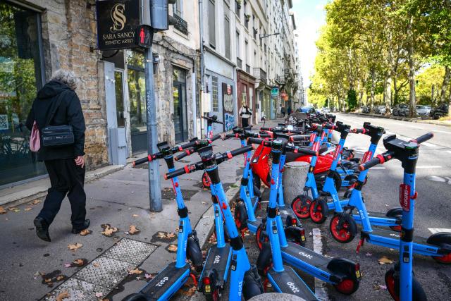 A pedestrian walks past electric scooters that have been disconnected in the vicinity of the city center, to ensure they are not used as makeshift barricades or obstacles in Lyon, on October 23, 2026 ahead of protests. France will deploy some 70,000 security personnel nationwide for new protests this weekend, Interior Minister said on October 23, warning that calls for violence and looting were already circulating on social media. (Photo by OLIVIER CHASSIGNOLE / AFP)