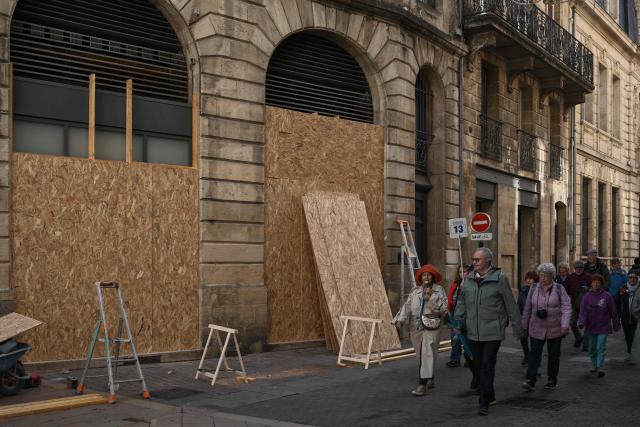 A guided tour group walks past boarded-up shops ahead of a demonstration planned for October 24, in central Bordeaux, southwestern France, on October 23, 2026. (Photo by Philippe LOPEZ / AFP)