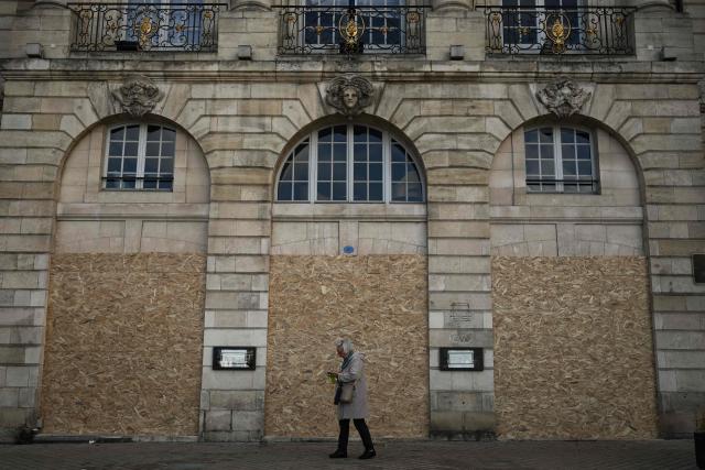 A woman walks past the boarded-up ground-floor windows of a historic building ahead of a demonstration planned for October 24, in central Bordeaux, southwestern France, on October 23, 2026. (Photo by Philippe LOPEZ / AFP)